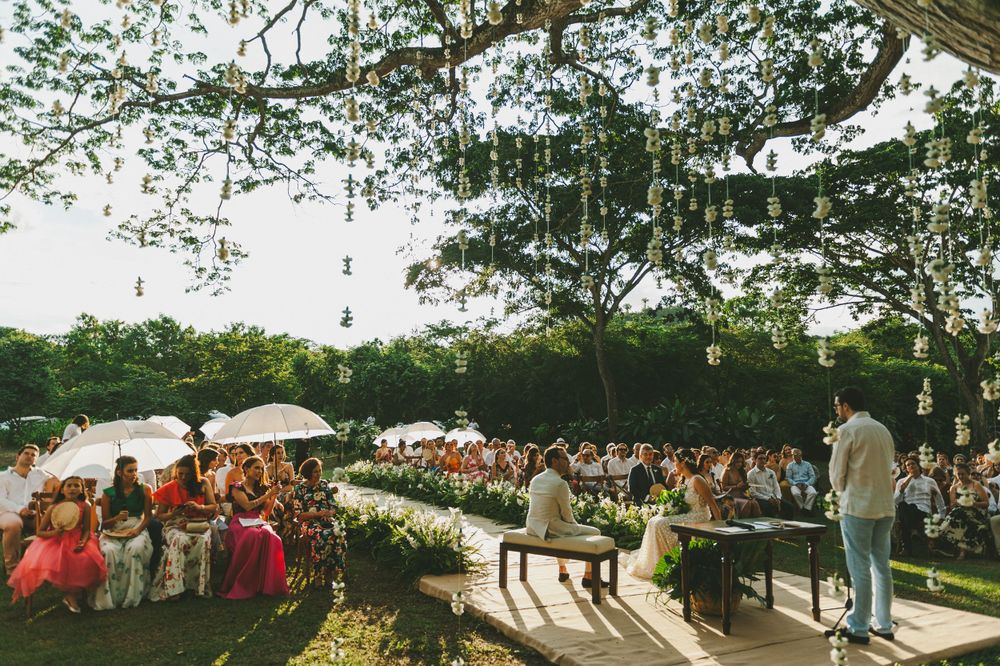 Outdoor wedding ceremony taking place in front of an ancient tree at sunset.