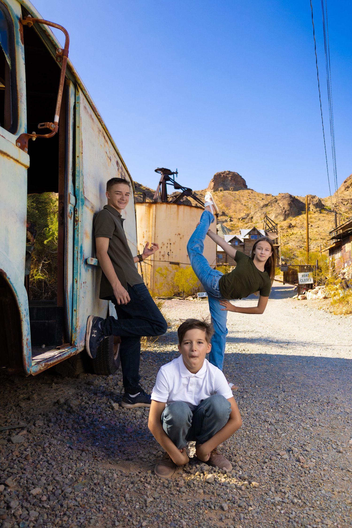 Creative portrait of dancers posing with old bus in desert landscape.