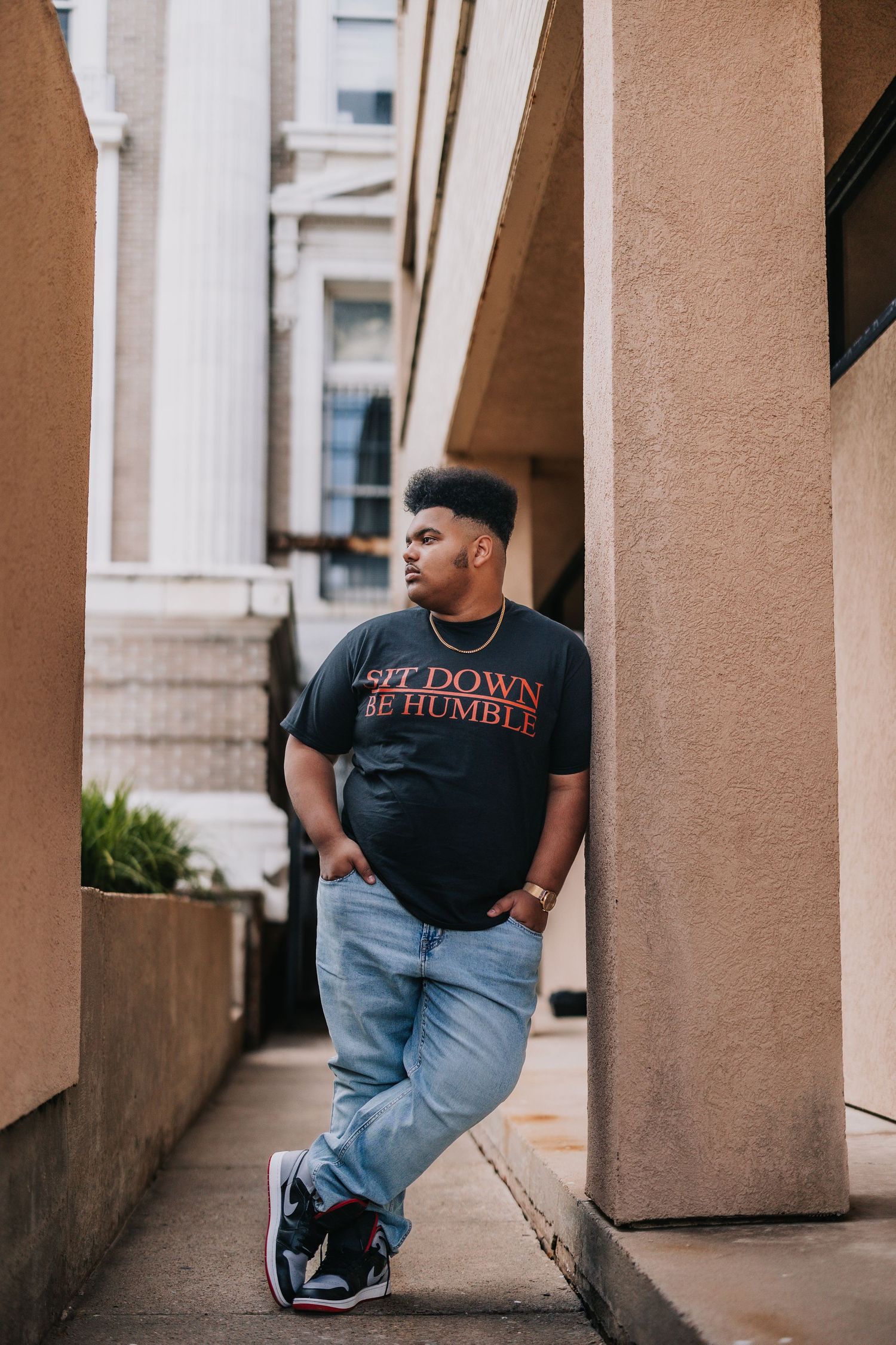 Urban photoshoot featuring casual street style poses against a beige building exterior.