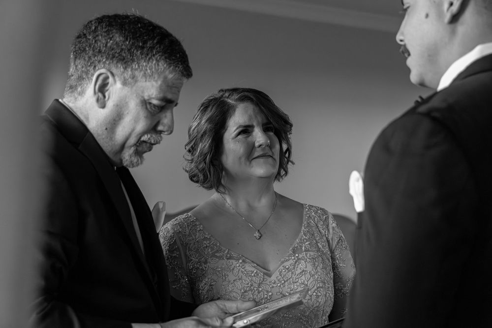 Black and white candid moment during a wedding ceremony showing emotional exchange between participants.