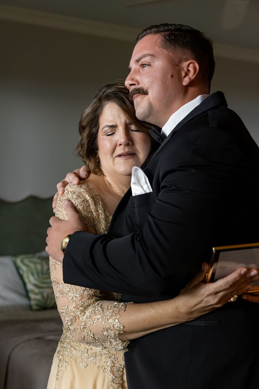 A couple shares an intimate dance in formal attire, with the bride wearing a sparkling gold dress.