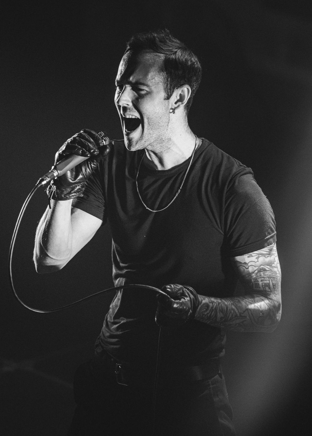 Black and white photo show a vocalist performing passionately on stage with dramatic lighting and intense expressions. Band is Body of Light