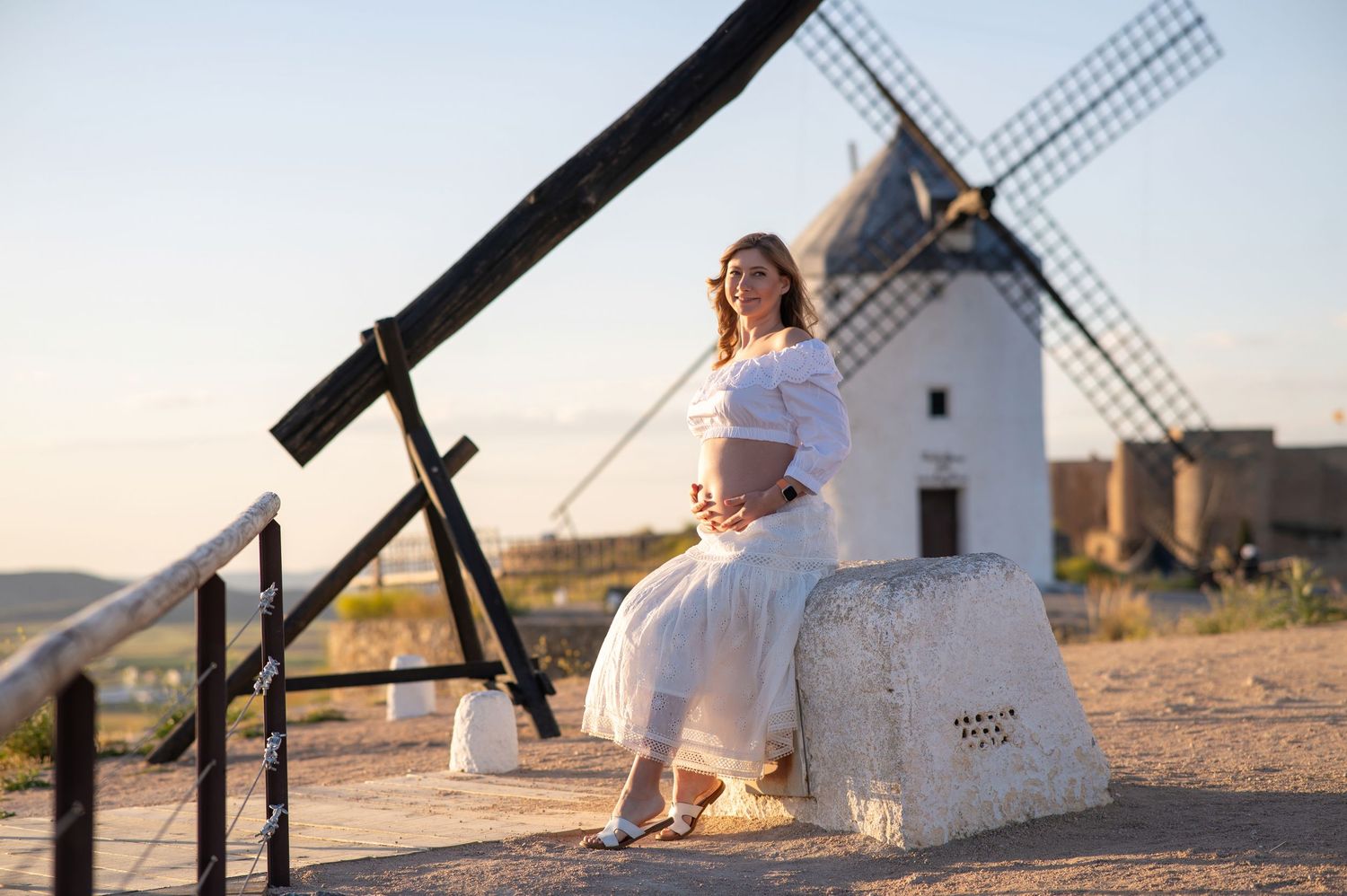 A scenic row of traditional white windmills against a golden sunset sky in Consuegra, Spain.