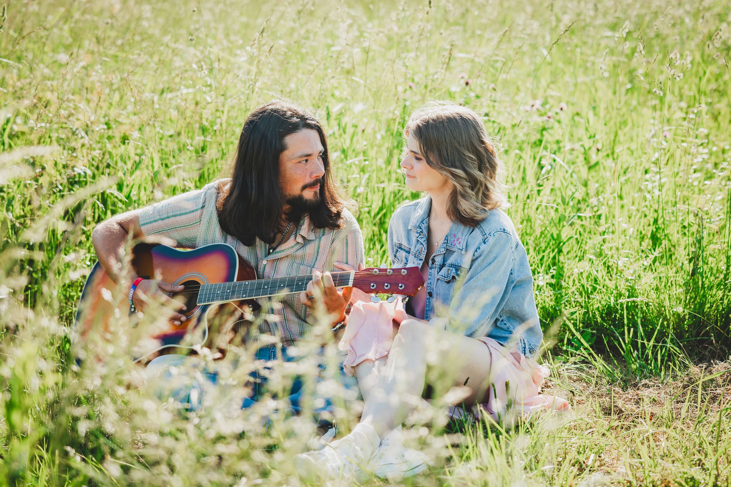 People enjoying a casual outdoor picnic gathering on a sunny day with food and drinks in a grassy field.
