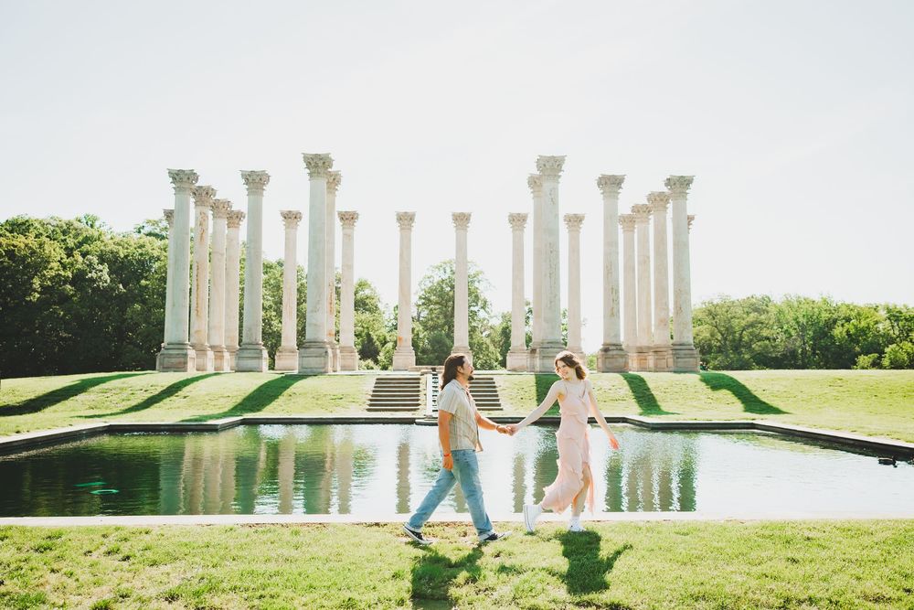 A couple poses at the National Arboretum's iconic white columns surrounded by lush green lawns and gardens.