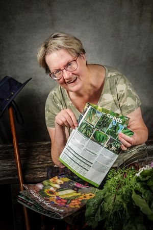 Someone joyfully opens seed packets while preparing to start a garden with fresh herbs and vegetables on a dark background.