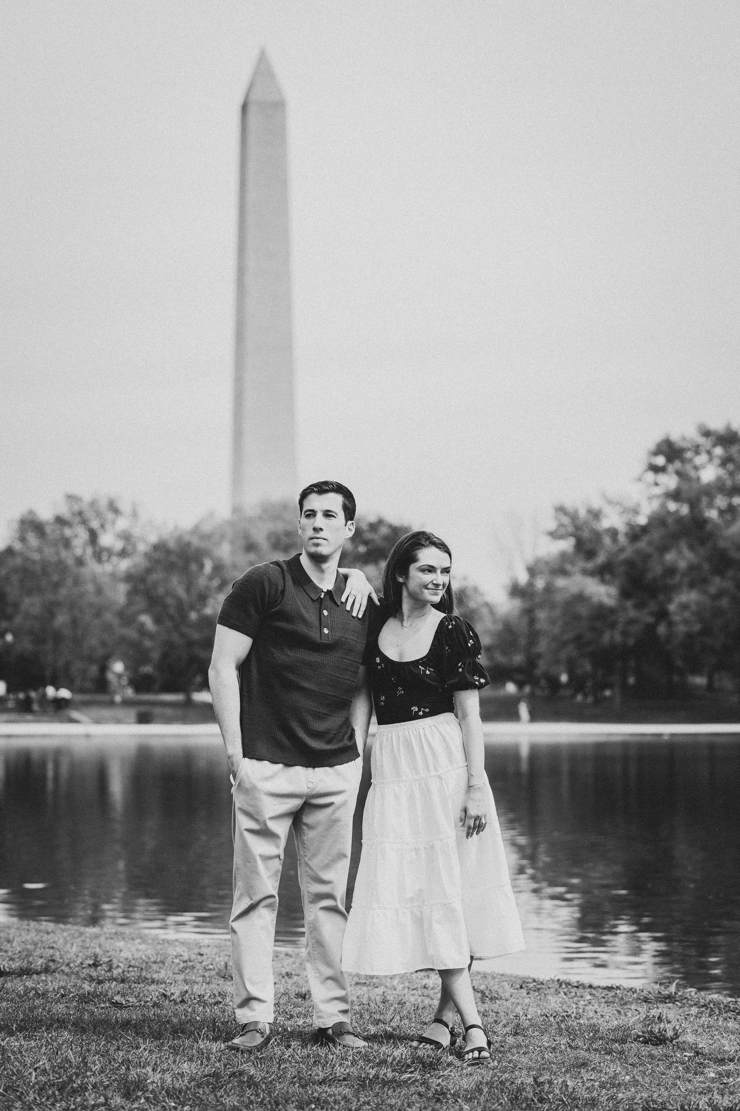A couple poses together near the reflecting pool with the Washington Monument in the background.