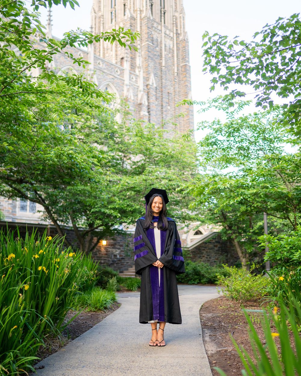 A series of graduation photos taken on a garden path with yellow flowers and Gothic architecture in the background.