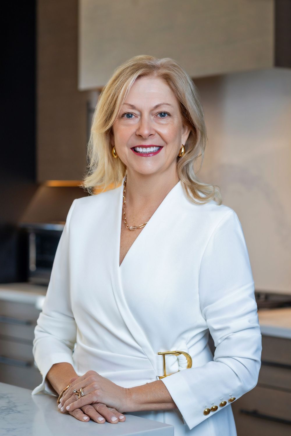 Professional business portrait series in white blazer against modern office background with warm lighting.