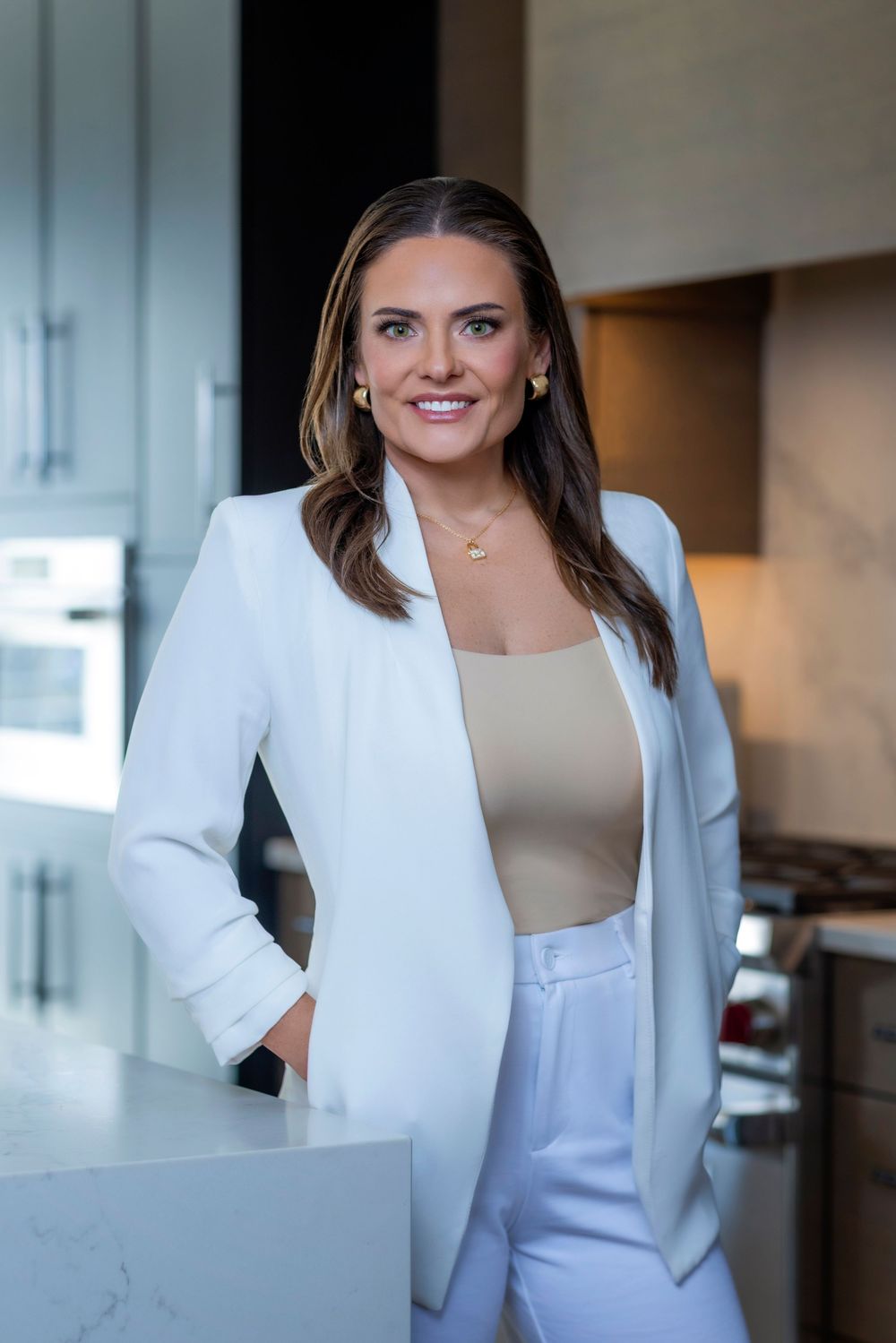 Woman wearing a stylish white blazer poses confidently in an office environment.