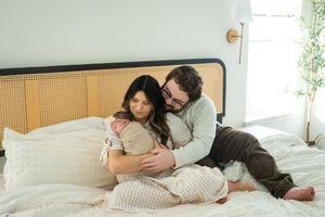 A couple relaxes together on a bed with rattan headboard in a cozy, sunlit bedroom.
