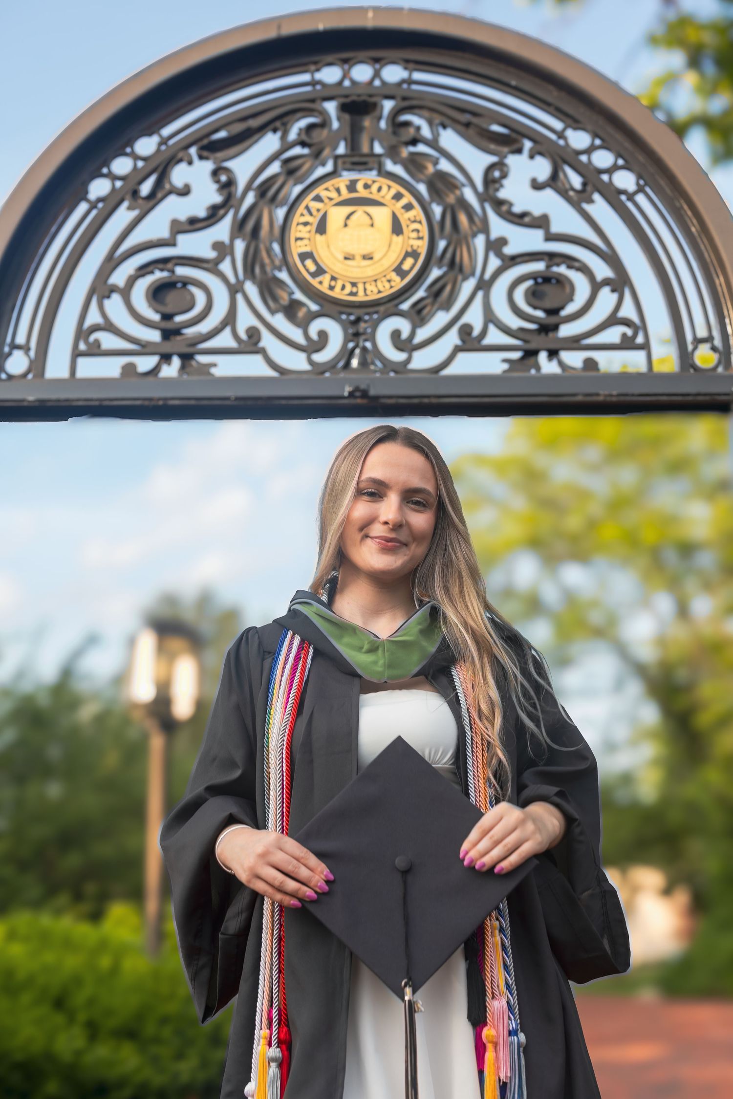 A graduation cap decorated with colorful tassels and ornate designs shown from multiple angles outdoors.