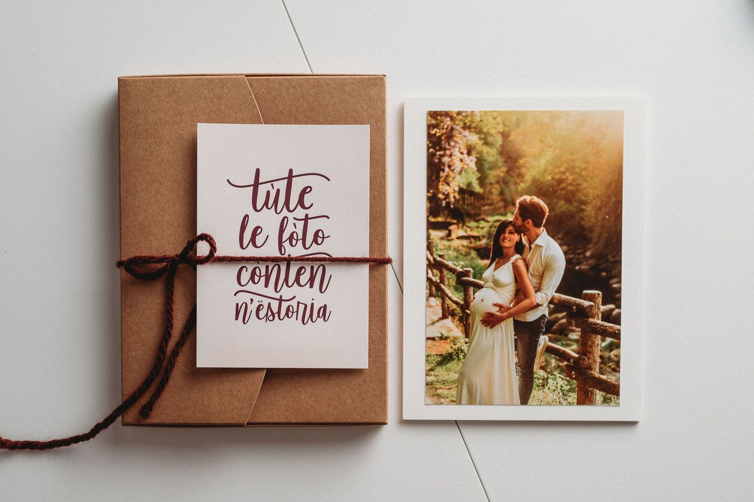 Flat lay of brown kraft paper gift boxes and cards with calligraphy text arranged in a row on white surface.