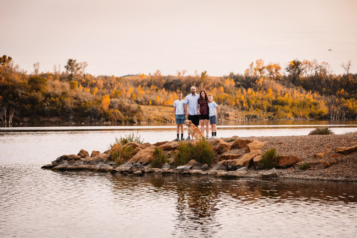 Scenic waterfront landscape with family portrait silhouetted against sunset.