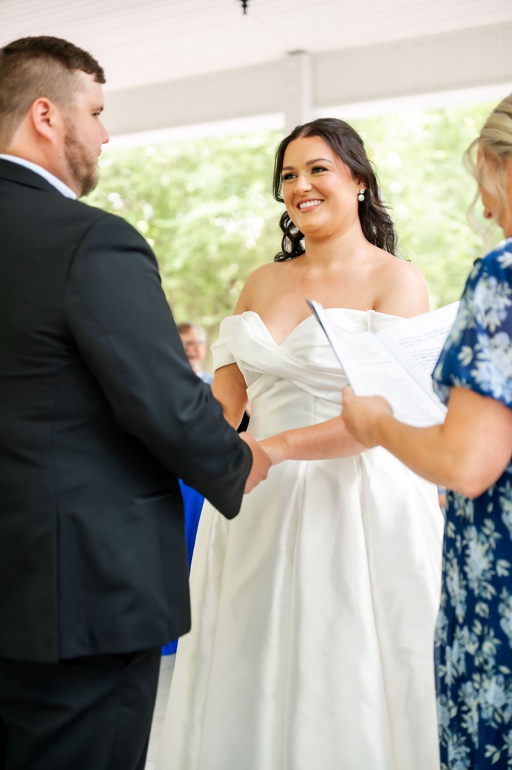 Wedding ceremony participants exchanging documents during an indoor service.