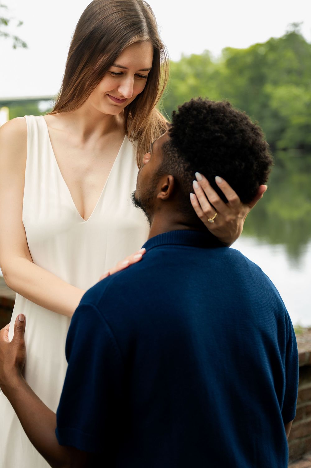 Romantic couple in white and navy blue outfits share intimate moments by a lake.
