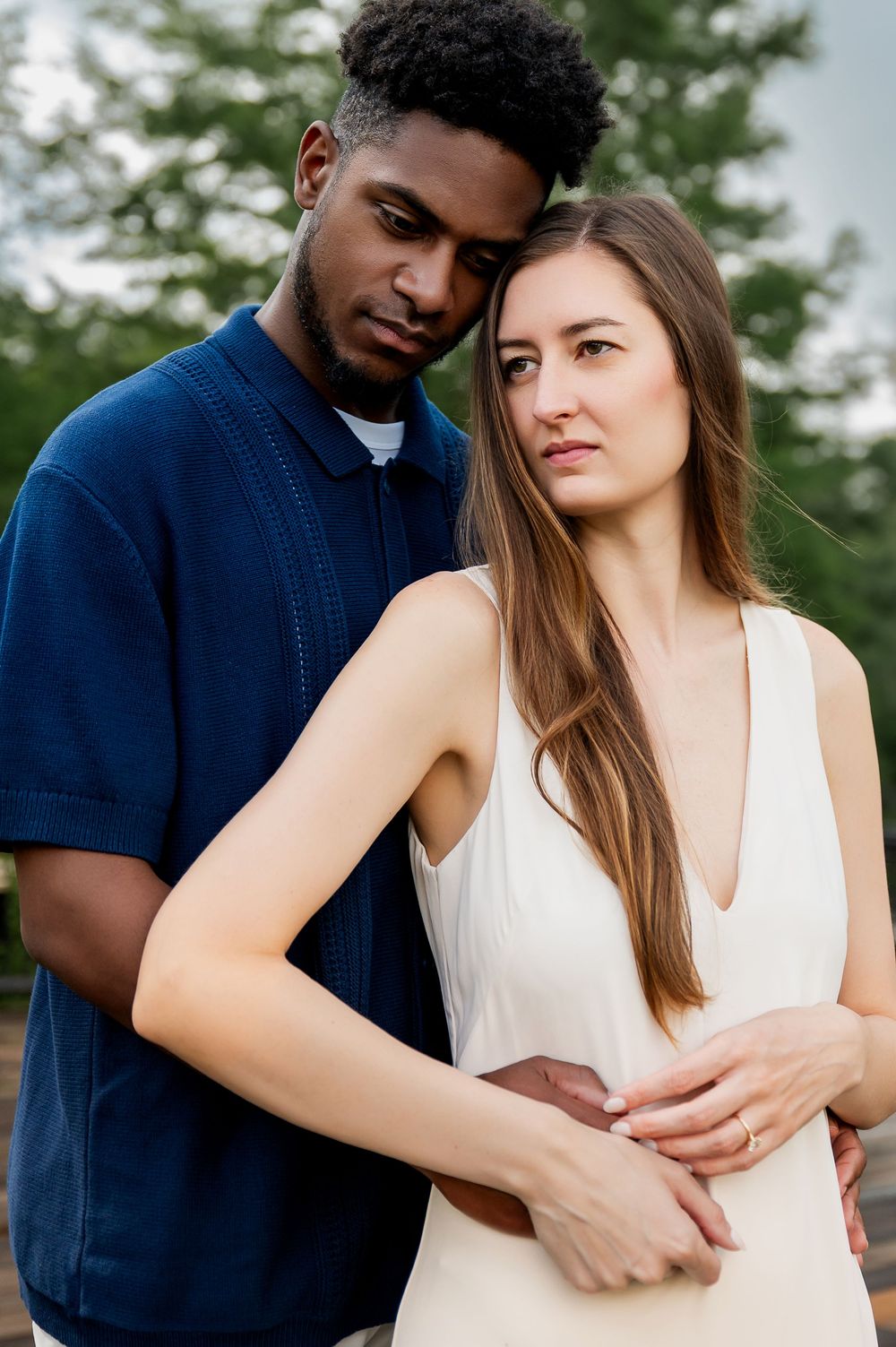 Couple in contrasting outfits embrace while sharing romantic moments outdoors.