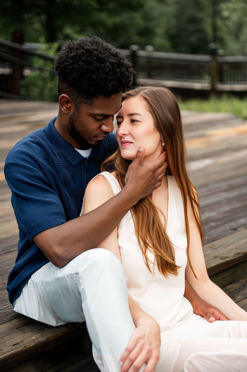 Couple shares tender moments while sitting together on wooden bench.