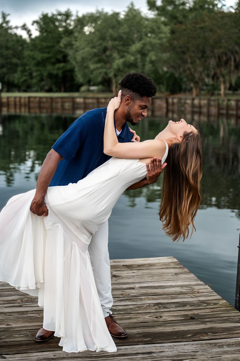 Romantic dip pose sequence on lakeside dock during couple photoshoot.