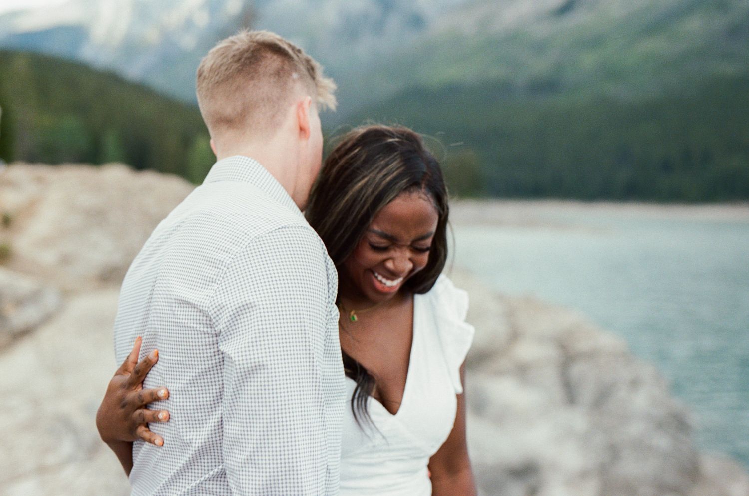 bride and groom laugh on the rocky shore of a lake in Kananaskis