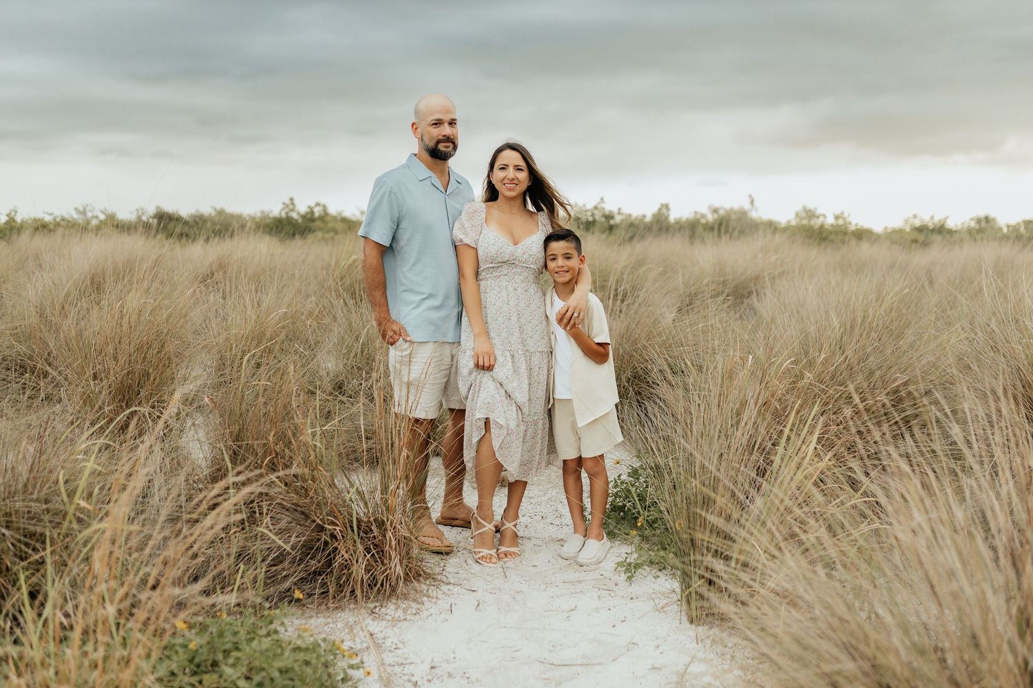 Family standing together in a grassy field during a lifestyle photography session.