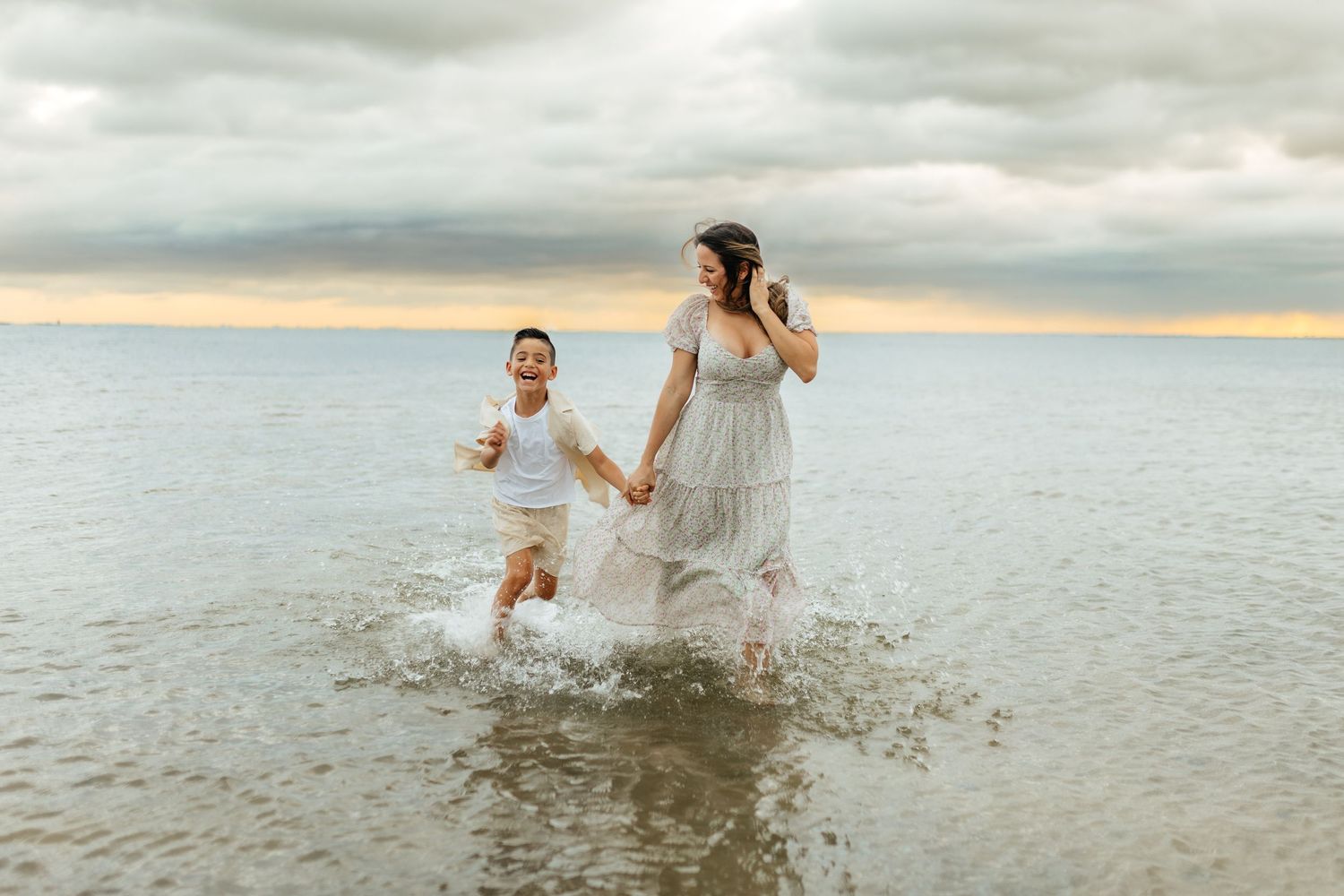 Mother and child walking through shallow water during a lifestyle family photography session.