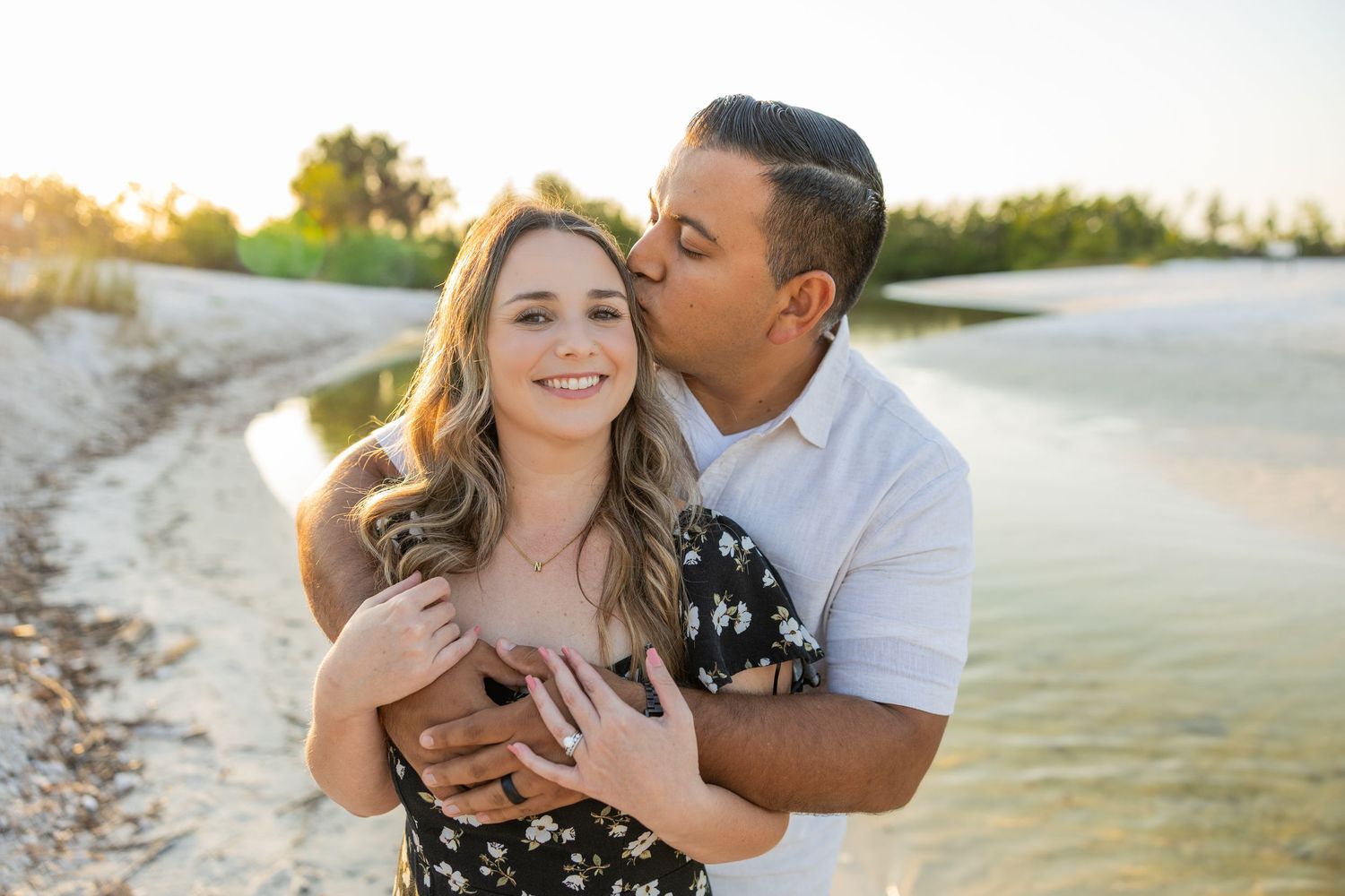 Couple embracing near the water during a lifestyle couples photography session at golden hour.