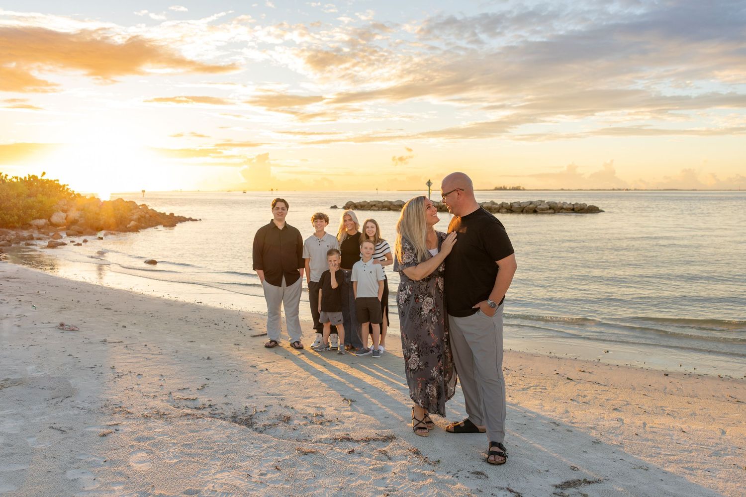 Extended family standing together on the beach during a sunset family photography session.
