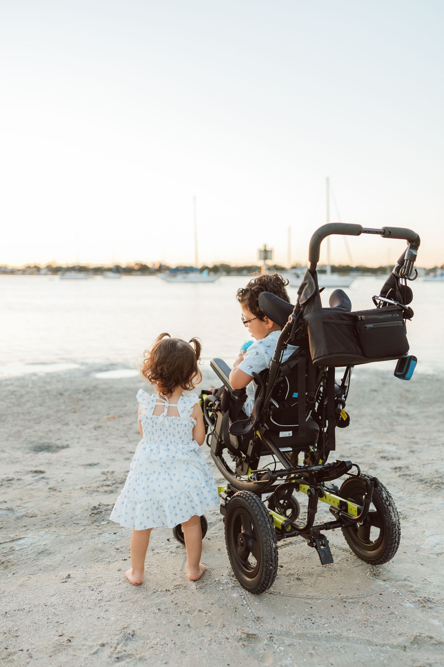 Young child pushing a stroller on the beach during a family lifestyle photography session.