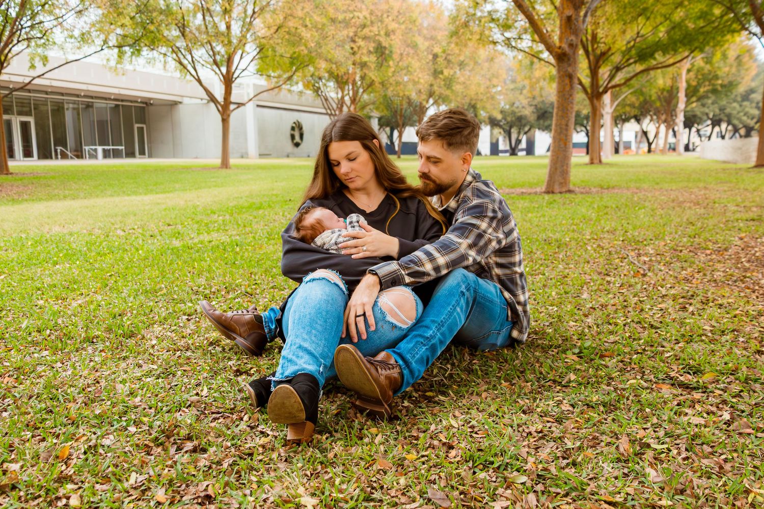 A couple relaxes together on autumn leaves in a park during a romantic outdoor photo session.