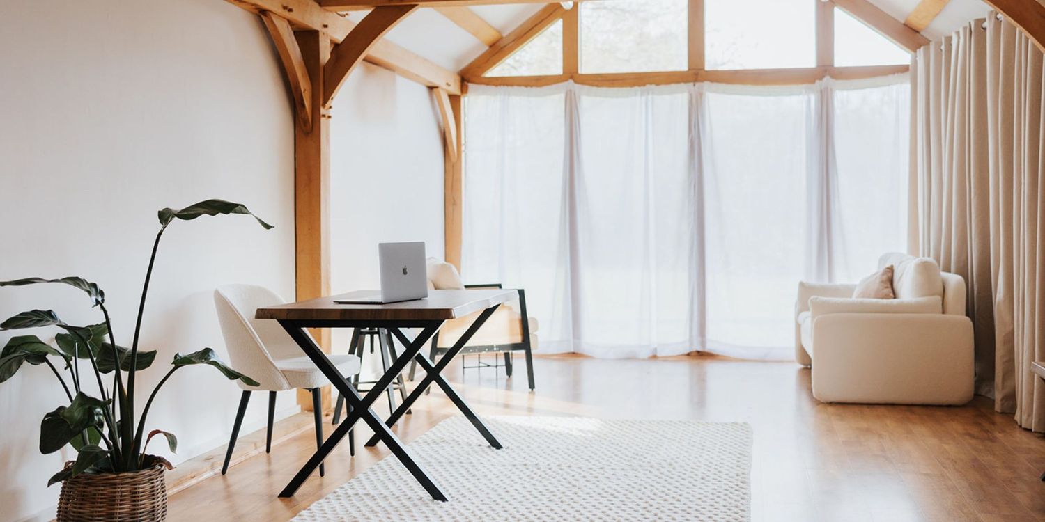 Modern minimalist photography studio with wooden beams, white walls, and large windows creating a bright, airy living space.