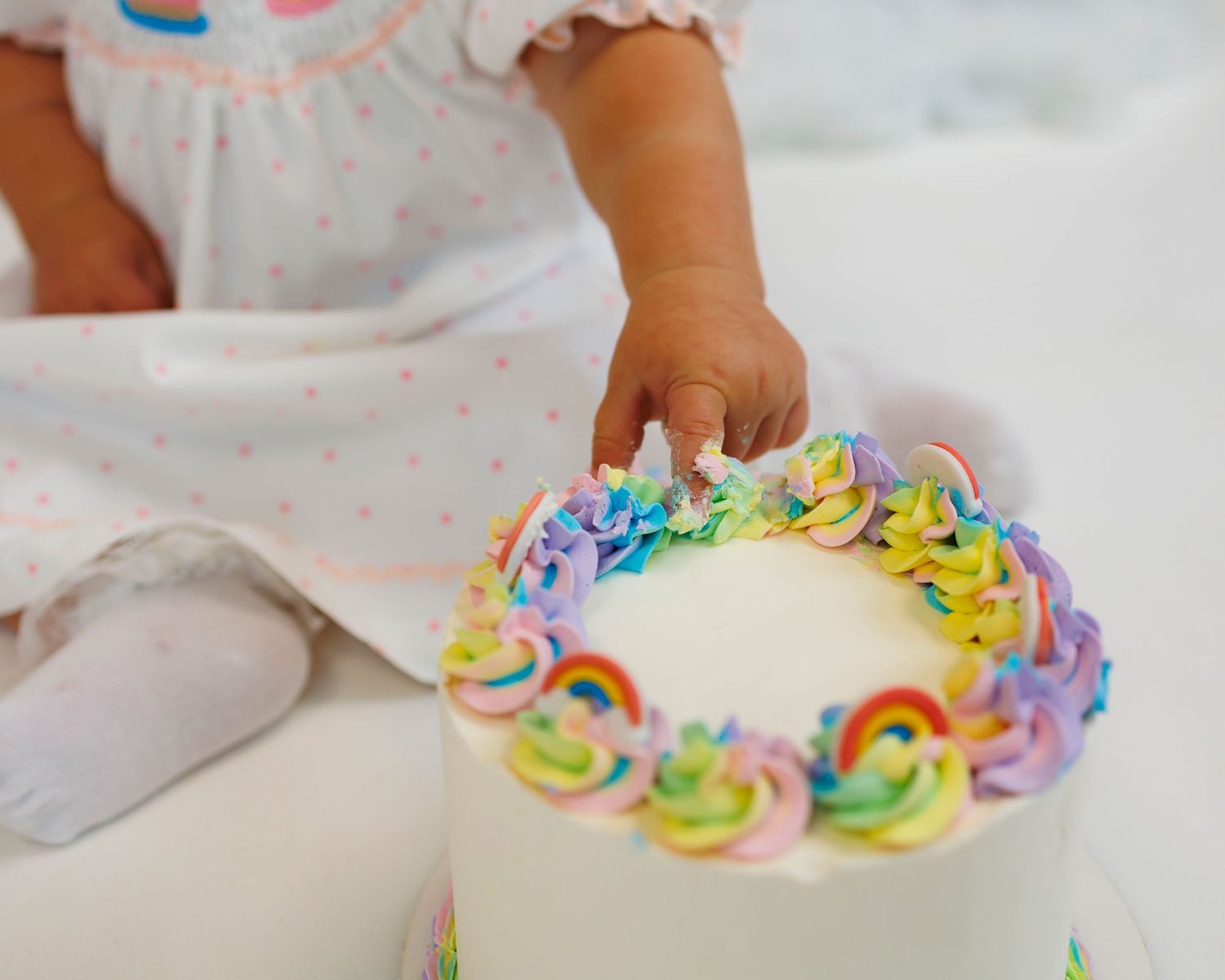 Colorful rainbow meringue cookies being arranged in a swirling pattern on a white surface.