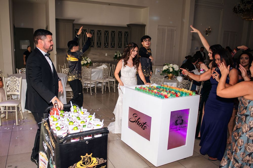 Wedding guests gather around illuminated candy buffet tables filled with colorful treats and sweets at an elegant reception.