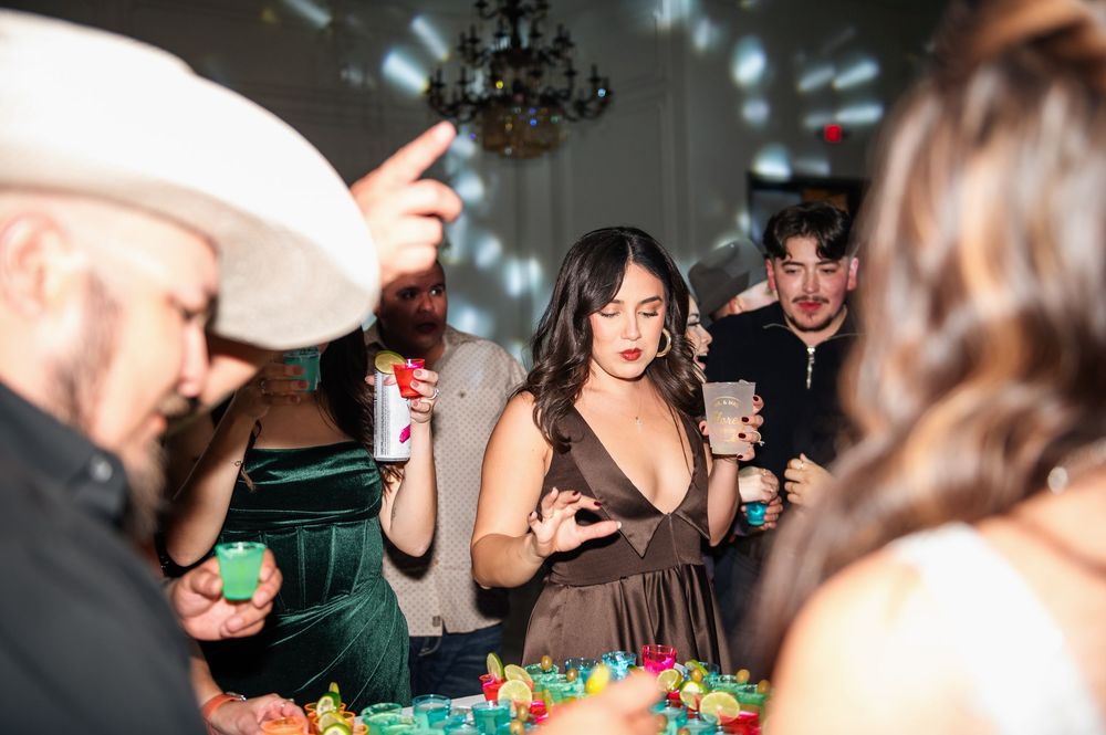 Party guests enjoying drinks and snacks at an indoor celebration with mood lighting and a chandelier.