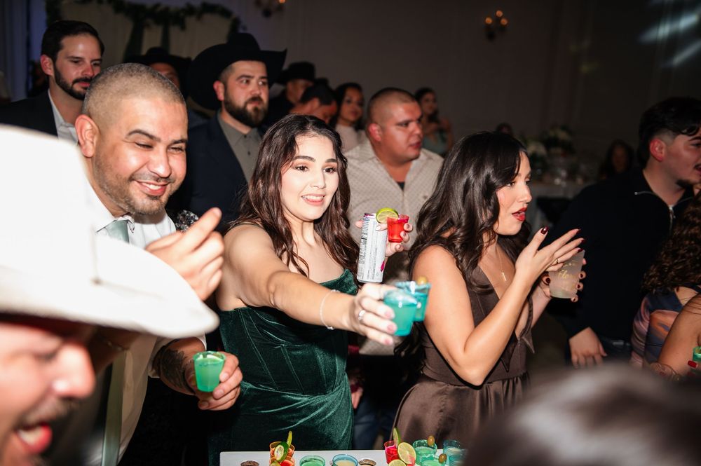 Festive crowd dancing and celebrating with drinks at a dimly lit indoor party.