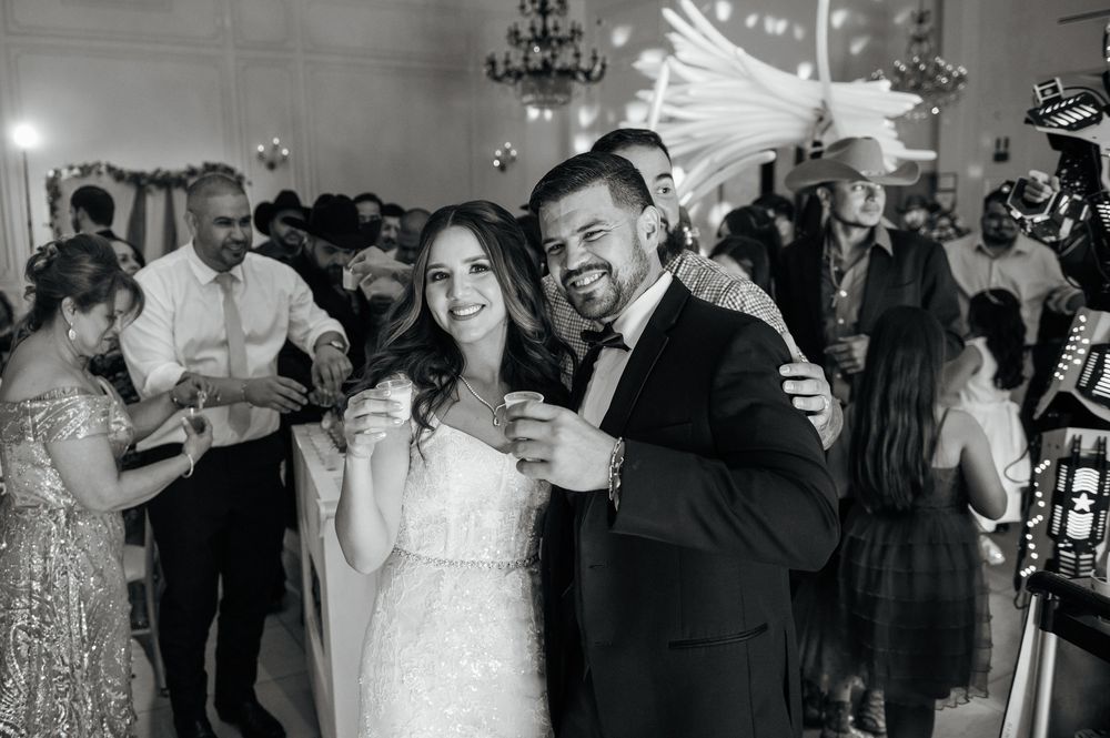 Wedding reception guests dancing and celebrating on a crowded dance floor under elegant chandeliers.