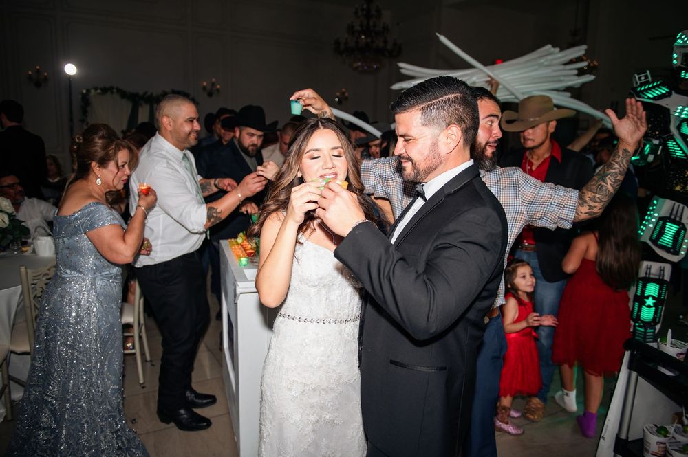 Wedding guests dancing and celebrating on a dimly lit dance floor at a reception party.