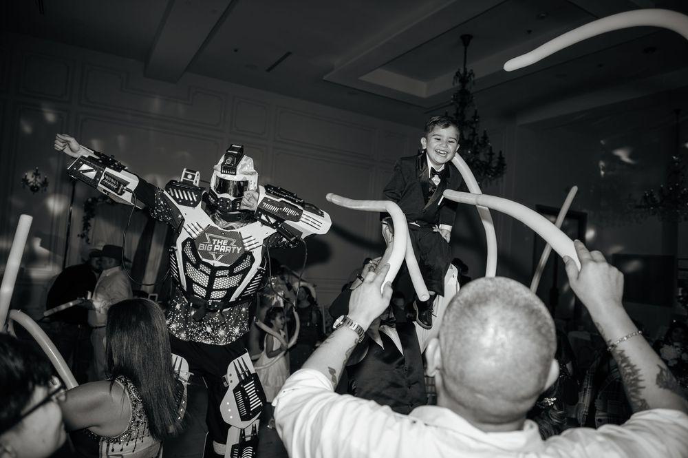Black and white photo of a crowded dance floor with hands raised during a party.