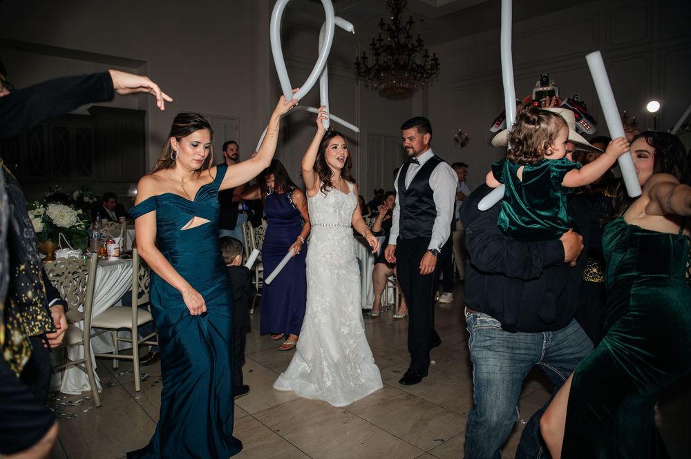 Wedding reception dance floor filled with guests dancing and celebrating in evening lighting.