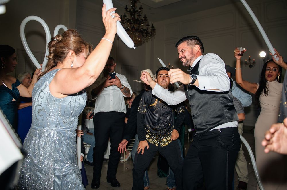 Energetic wedding party dancing and having fun during evening reception celebrations.