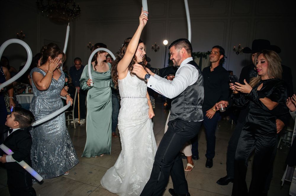 Lively dance floor scene with wedding guests enjoying themselves under dim lighting.