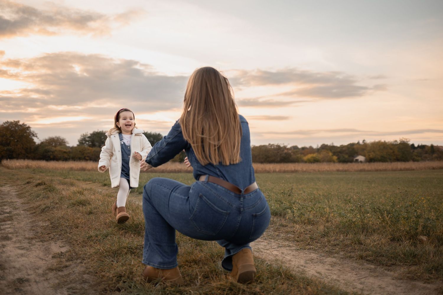 A photographer captures a moment between two people in a golden sunset field.