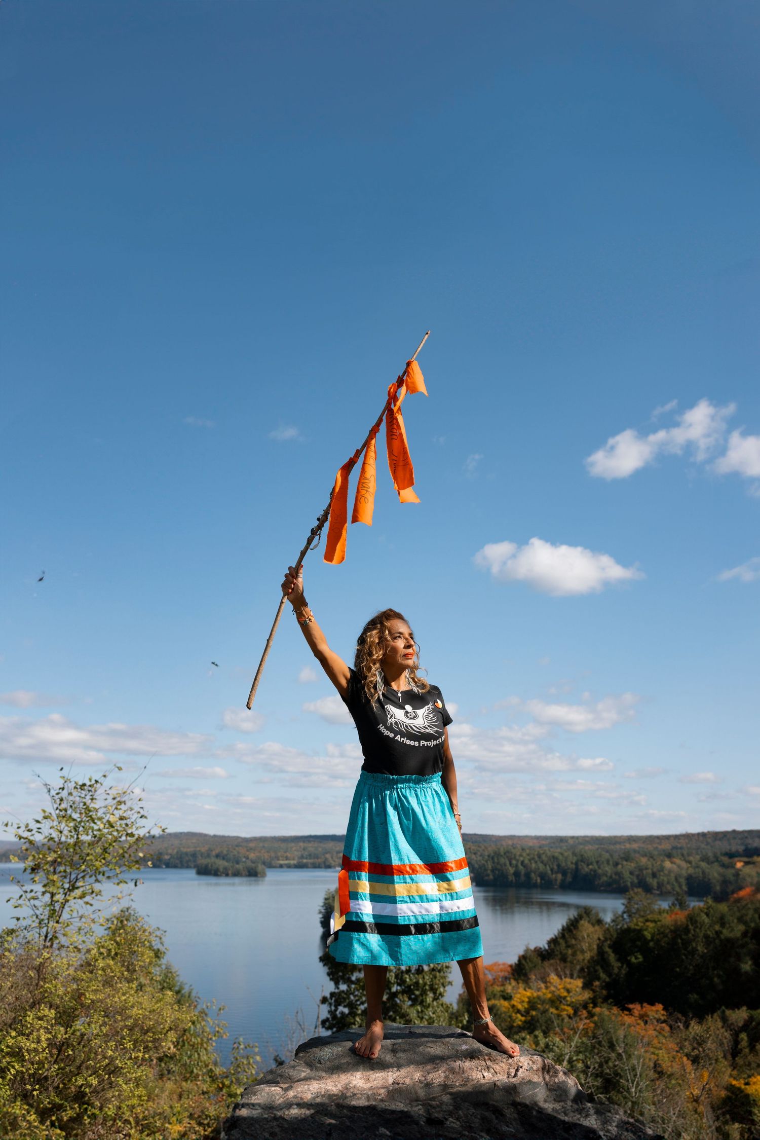 A sequence of photos shows a person in a turquoise sweater celebrating on a rocky overlook above a scenic lake view.