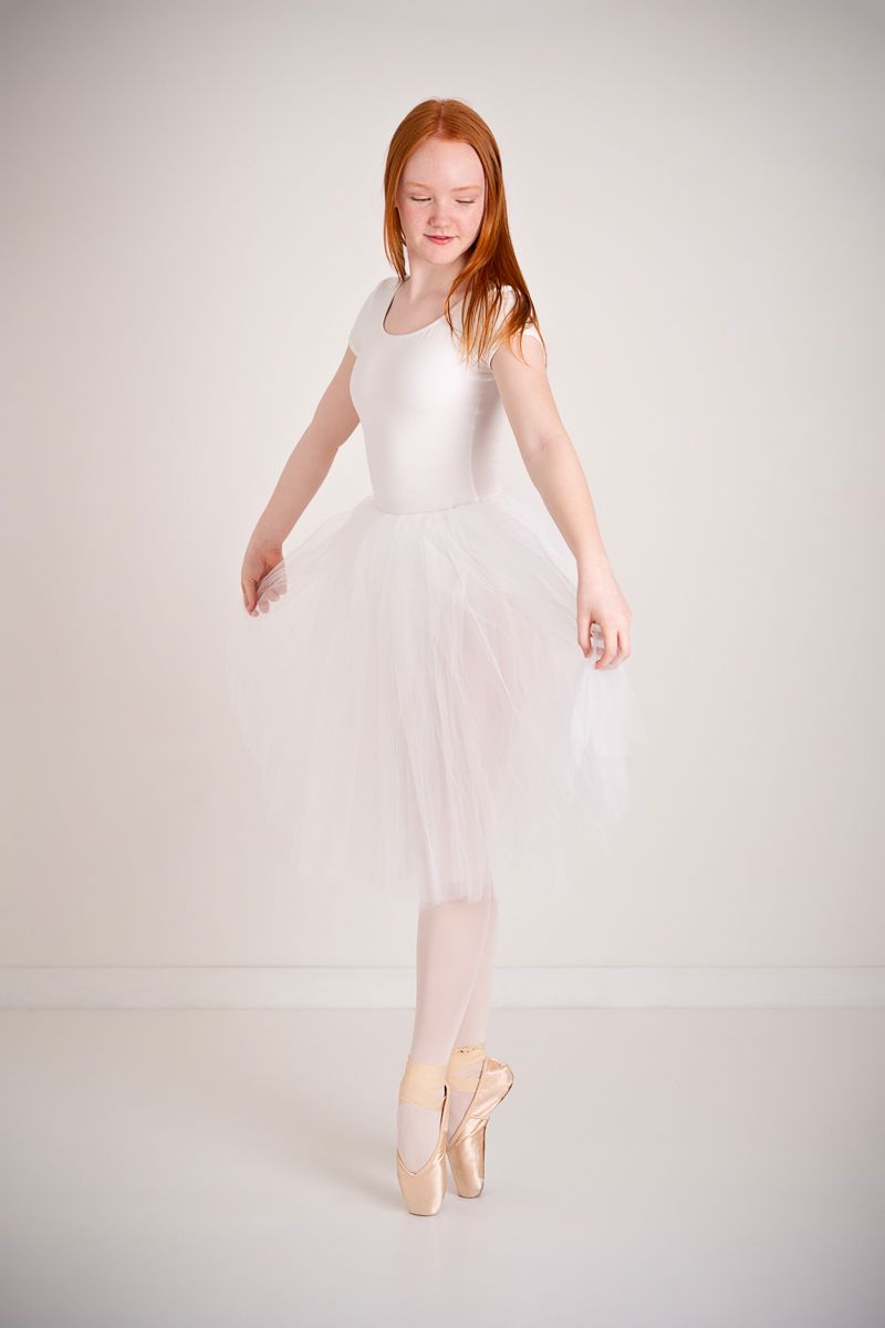 Dancer with red hair and white long tutu pose naturally in studio Cobourg Ontario, for dance photography session*