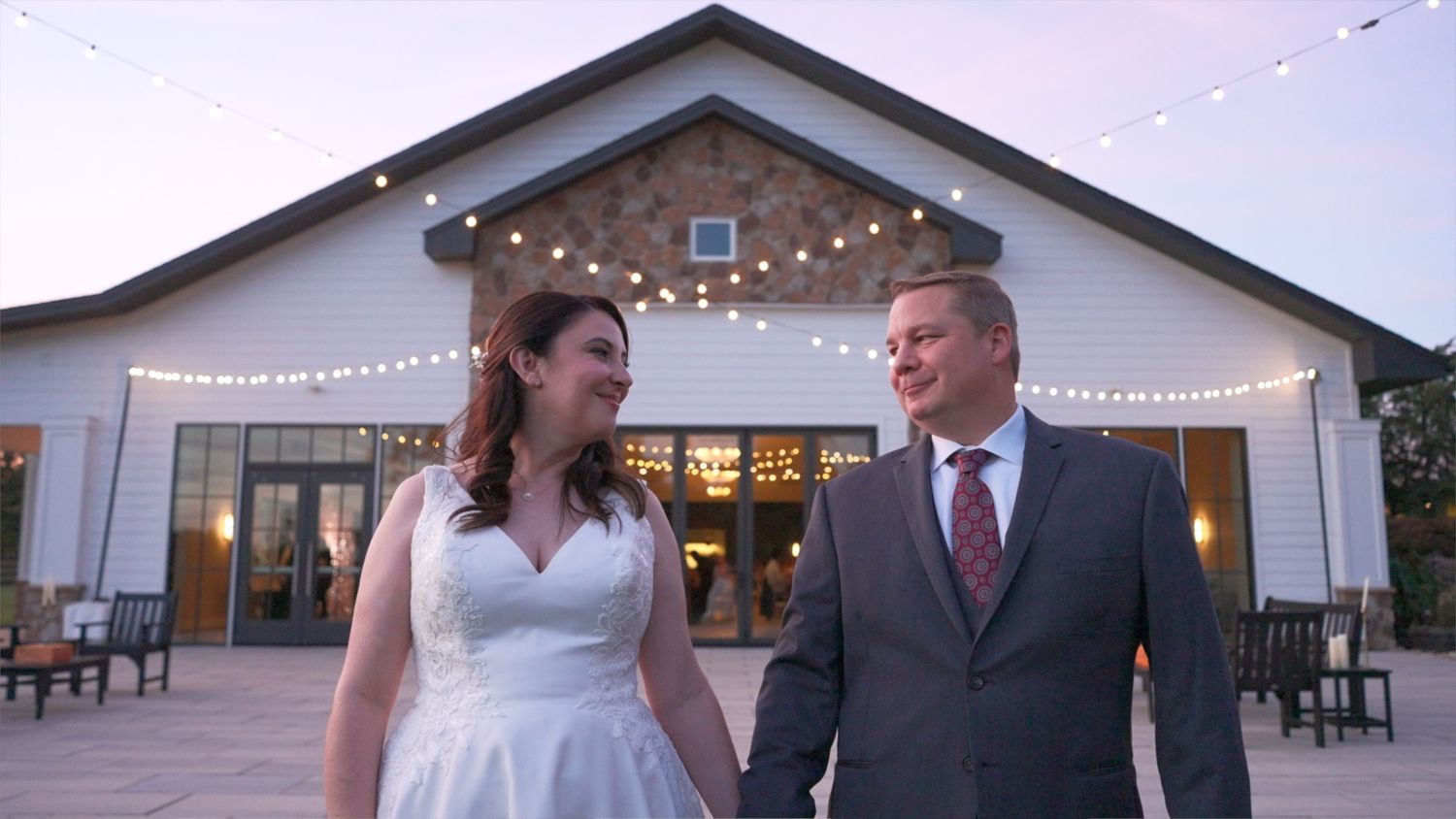 Wedding reception venue with string lights and elegant outdoor setup at dusk.