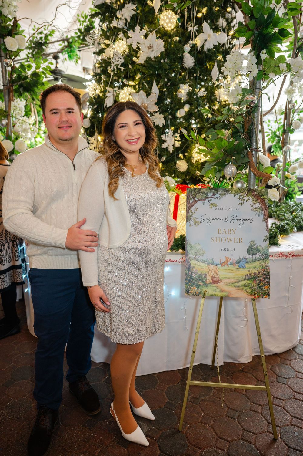 A couple poses next to signage for their Winnie the Pooh themed baby shower in Huntington, Long Island.
