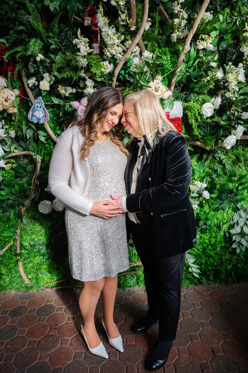 Two figures share an intimate moment in a lush garden setting with white floral decorations and hexagonal tile flooring.