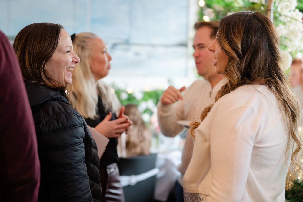 Wedding guests share laughter and conversation during an outdoor reception celebration.