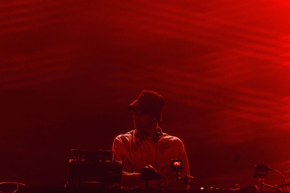 A dramatic red stage lighting effect creates an atmospheric glow across a dark performance space.