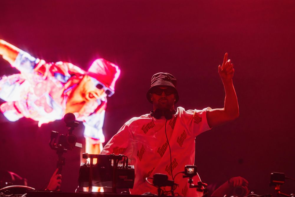 Concert stage illuminated with dramatic red lighting and smoke effects during a live performance.
